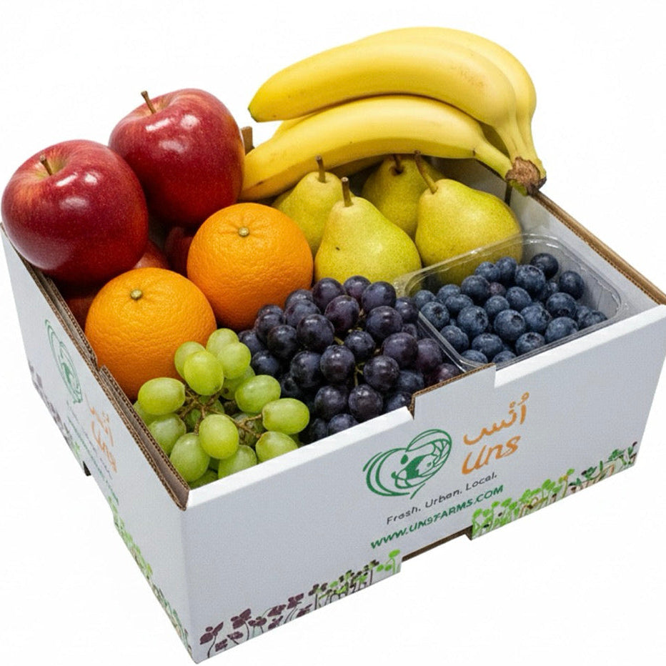 Assorted fruits including apples, oranges, bananas, pears, and grapes in a box with a visible brand logo on a white background.